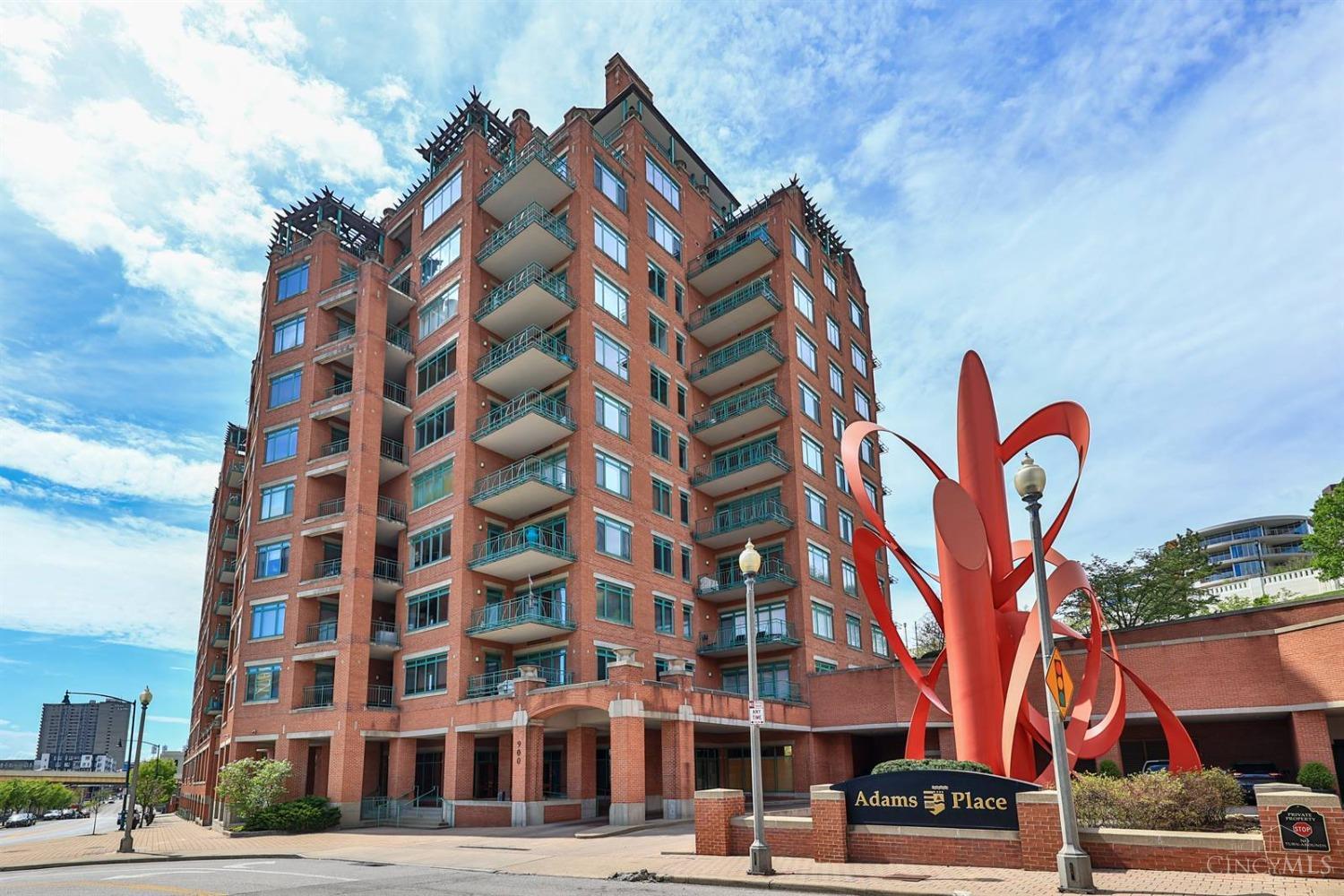 Elegant 10th floor condo home in Cincinnati's premier riverfront condominiums: Adams Place. First class luxury living with incredible views of the River, Sawyer Point, Daniel Carter Beard Bridge, the City skyline, and Mt Adams. The home includes two bedrooms with en-suite bathrooms, the primary with cedar lined walk-in-closet; open living and dining rooms; den with gas fireplace, built-ins and wet bar, rich hardwood flooring, traditional moldings; two spacious balconies; guest half bath; many closets; and laundry room. The updated kitchen includes granite countertops and subway glass tile backsplash. New SS appliances and heat pump installed in 2024. The building features around the clock staff concierge, gym with sauna, library, receiving hall, limo service, guest parking, onsite guest rooms, gated dog park, heated pool, gorgeous grounds, putting green, fire pit, and grilling station. Adams Place is a sought after location across from Sawyer Point tennis and pickle ball courts.