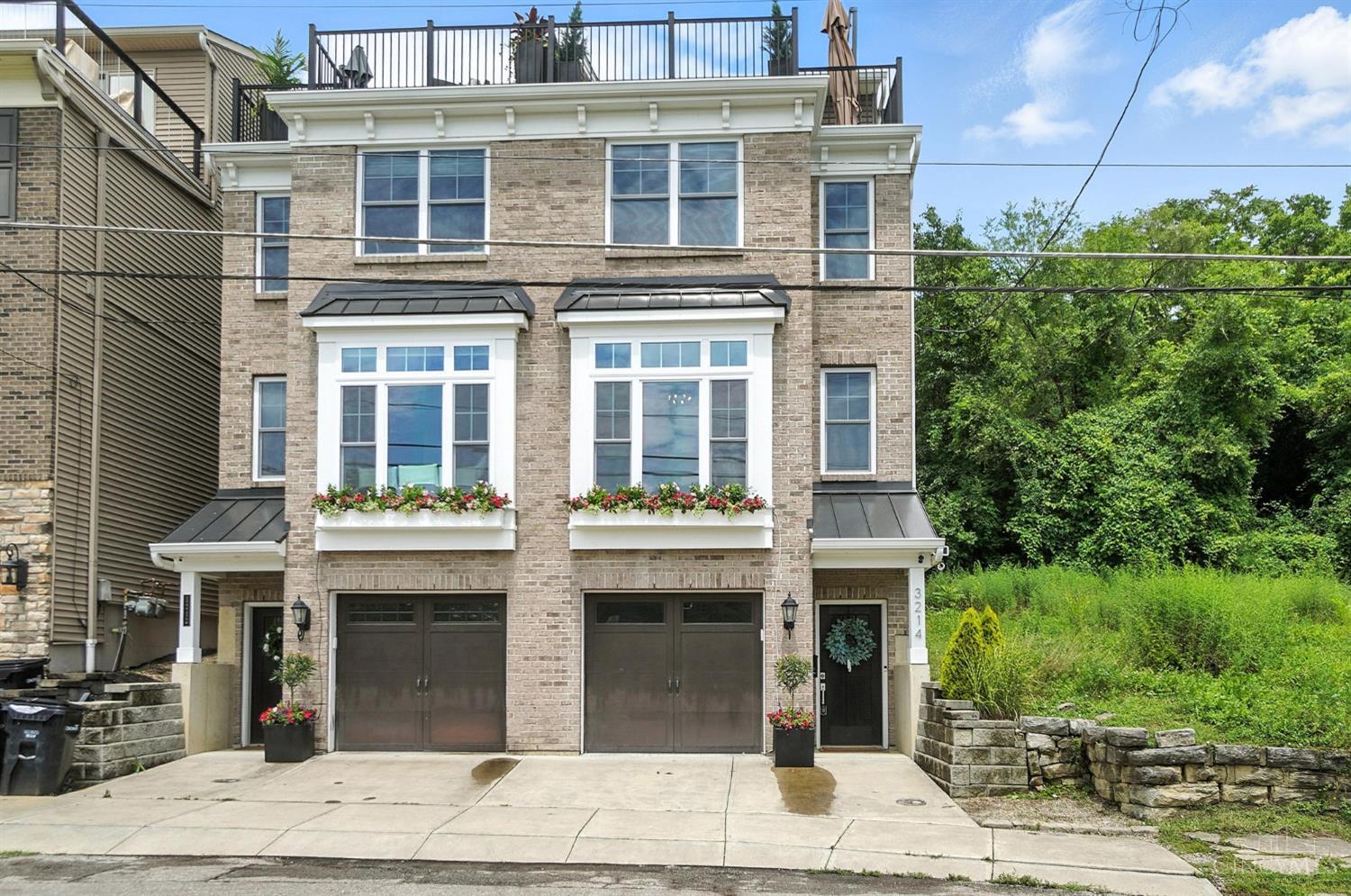 Discover your dream home in the city! This meticulously designed 3-bedroom, 3.5-bath residence offers an exceptional lifestyle. Inside, you'll find elegant hardwood floors and a gourmet kitchen featuring granite countertops. Step outside to a charming patio with a firepit, perfect for cozy evenings. The 3rd floor delights with a wet bar and wine cooler, leading up to an incredible rooftop deck. Here, panoramic Cincinnati skyline views await, alongside convenient access to greenspace and walking paths. Includes a tandem garage.
