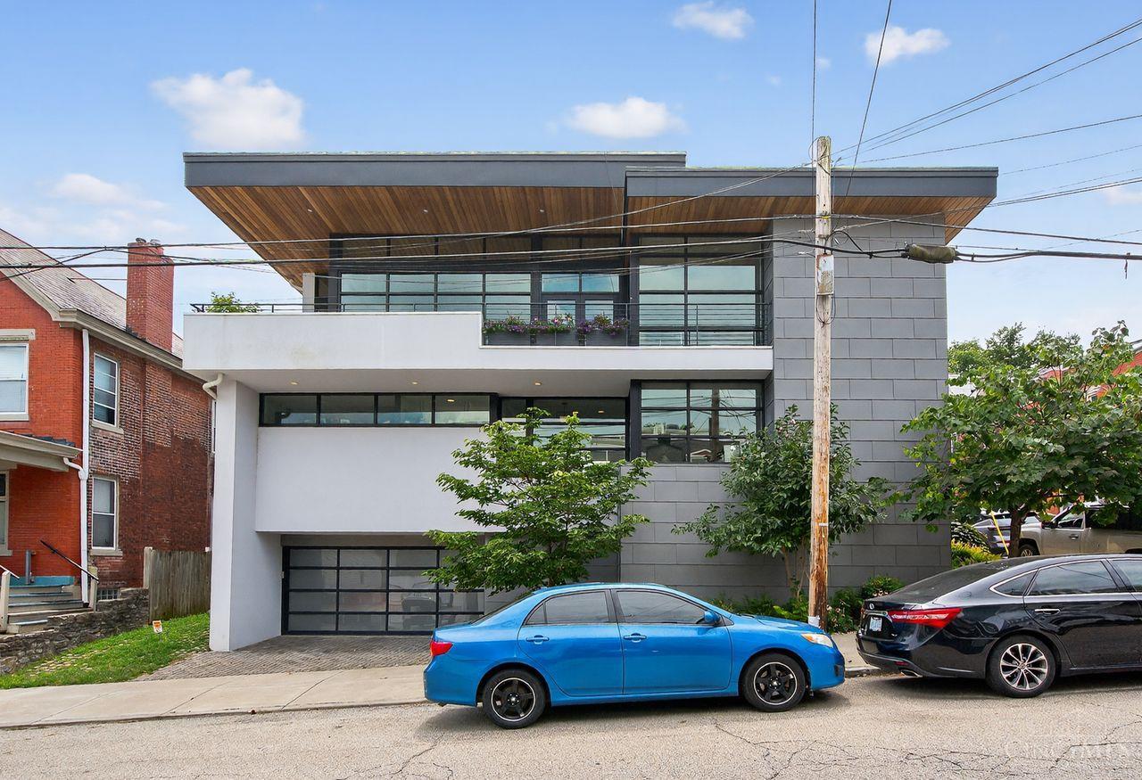 Welcome to The Trillium House - a Mt. Adams masterpiece by Tisley Architects where European-inspired charm meets modern urban living. This 4-bed, 4-bath LEED Platinum home with tax abatement through 2032 blends historic warmth with contemporary, sustainable design. Enter through the gated courtyard with water feature into an airy open floor plan filled with natural light from soaring ceilings and walls of glass. Reclaimed doors/floors, an elevator, multiple outdoor spaces, rooftop deck with river views, and solar panels offer style and convenience. The gourmet kitchen centers the entertaining space, complemented by a two-sided fireplace. The primary suite opens to the courtyard with a spa-like bath. Every bedroom has an ensuite, plus bonus spaces like a workshop, hot tub, and ample storage. Steps to dining and entertainment, The Trillium House is an urban sanctuary.