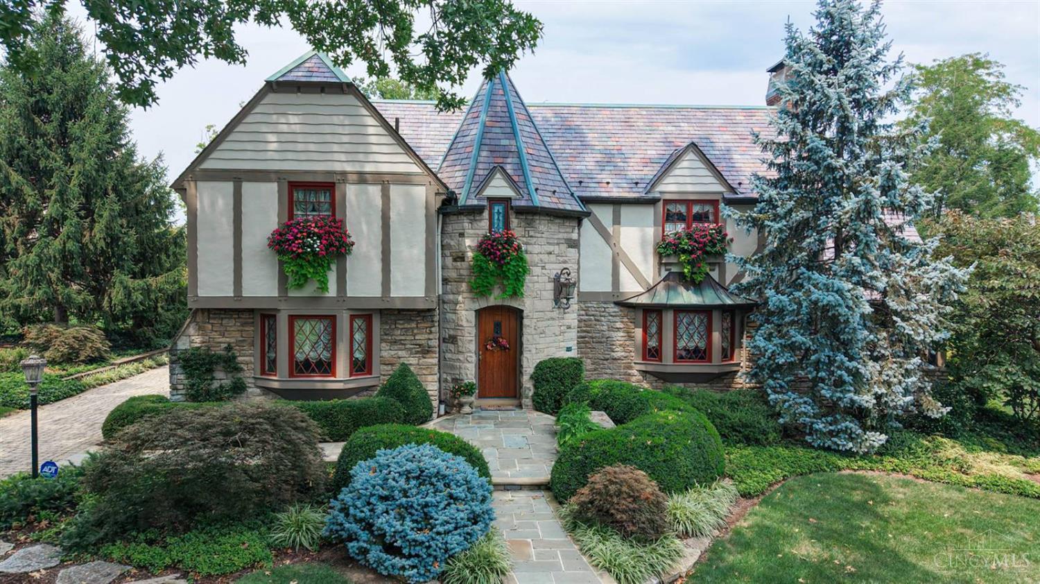 Meticulously maintained  Tudor nestled on coveted private drive. The exceptional stewardship of  this home shines through in the fastidious improvements., enhancing it's timeless character.  Slate roof, copper gutters, and Pella windows with stained glass overlays. Inside the 3,200 sq' living space is rich hardwood flooring, natural woodwork complementing the dramatic staircase, custom built-ins,  two gas fireplaces and enclosed porch. Chef-inspired Auer kitchen boasts high end appliances. The primary bedroom en-suite bath offers lofted ceilings, a sitting area, with an expansive dressing room, The finished, waterproofed lower-level features a large tile-floored rec room, custom cabinetry, new glass block windows, storage  and a newer Carrier HVAC system. Dreamlike outdoor space with a paver driveway, a custom limestone and quartzite patio and walkways, fireplace and fountain, framed by lush professional landscaping, Let this home be your next (and best) chapter.