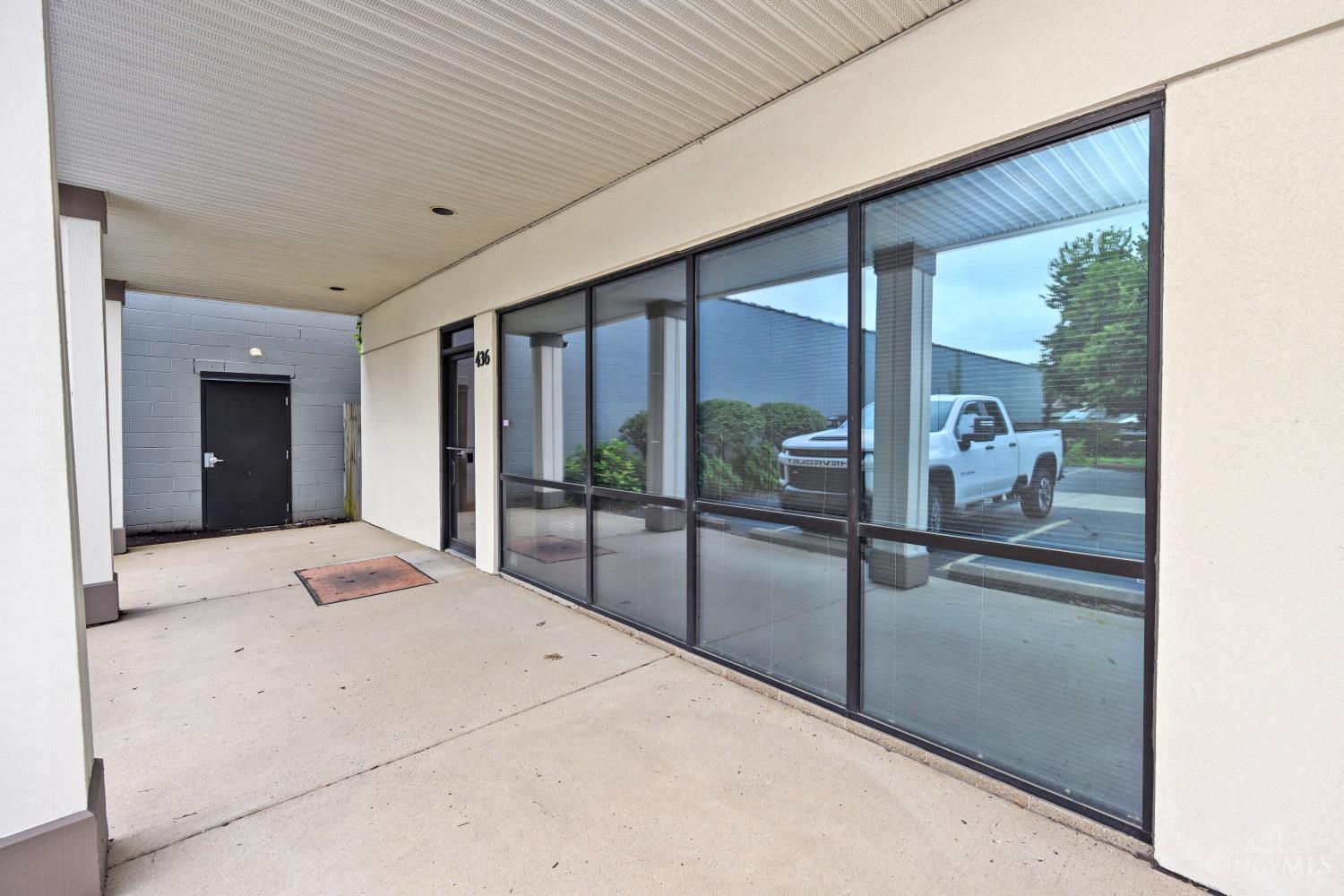 Commercial building entrance with covered walkway, glass storefront windows, and a door marked 436.