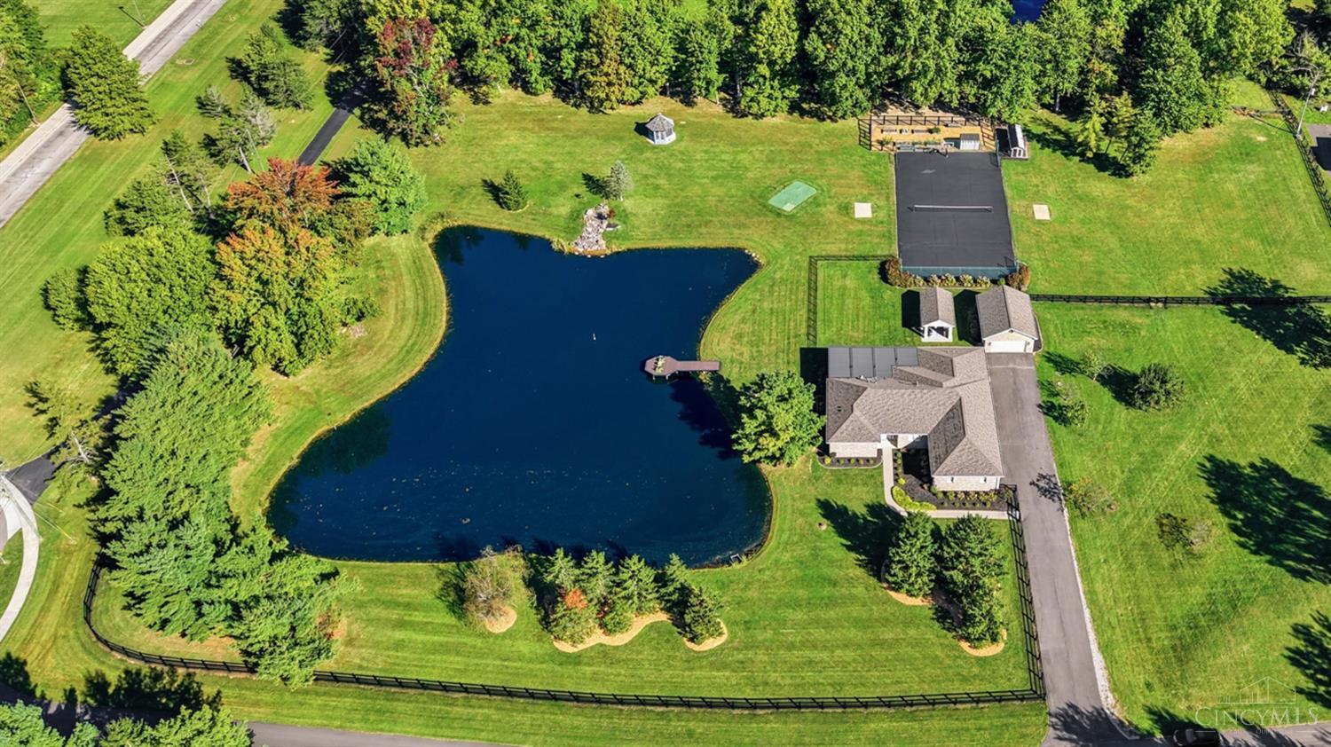 A truly extraordinary private retreat, this stunning custom brick ranch is set on 5 fully fenced acres where luxury, leisure & entertaining come together beautifully. The exceptional grounds feature a stocked fishing pond with dock, gazebo, fire pit, putting green, raised garden beds, chicken coop/run, sport court, outdoor kitchen & expansive covered patio overlooking serene private views. Inside, the open-concept design showcases a spectacular kitchen, inviting living room with fireplace & custom built-ins, formal dining room, office nook & luxurious primary suite with his & hers closets and spa-inspired bath featuring a soaking tub, walk-in shower, dual vanity, water closet & heated floors. The expansive lower level offers a wine tasting room, workshop, full bath & sauna. Geothermal heat, extensive improvements, & garages for up to 7 vehicles complete this exceptional offering. A remarkable property designed for refined livingand endless fun.